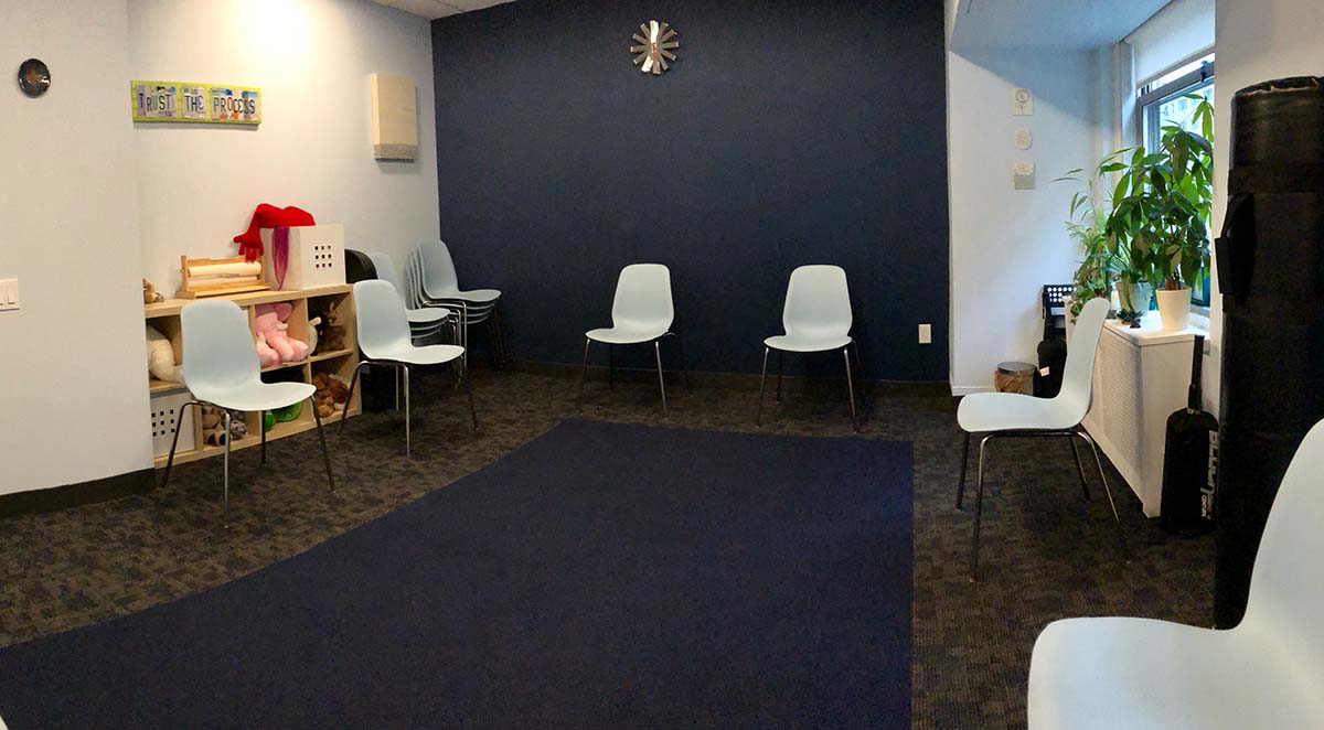 The practice space room, with chairs and props and an open area with a dark rug in the center